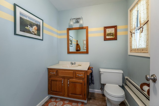 half bathroom featuring a baseboard radiator, vanity, toilet, and baseboards