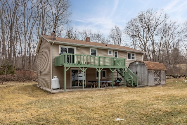 rear view of property with an outbuilding, a chimney, a lawn, a deck, and a shed