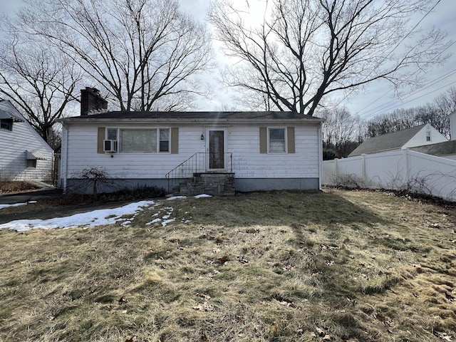 view of front facade featuring a front yard, fence, and a chimney