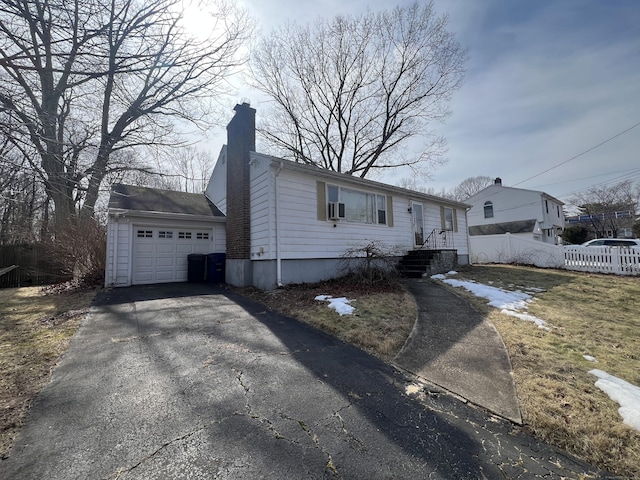 view of front facade featuring driveway, a chimney, and fence