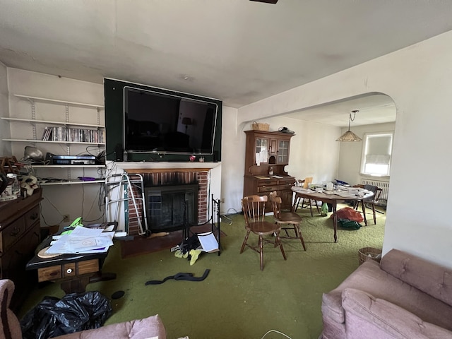 living area featuring arched walkways and a brick fireplace