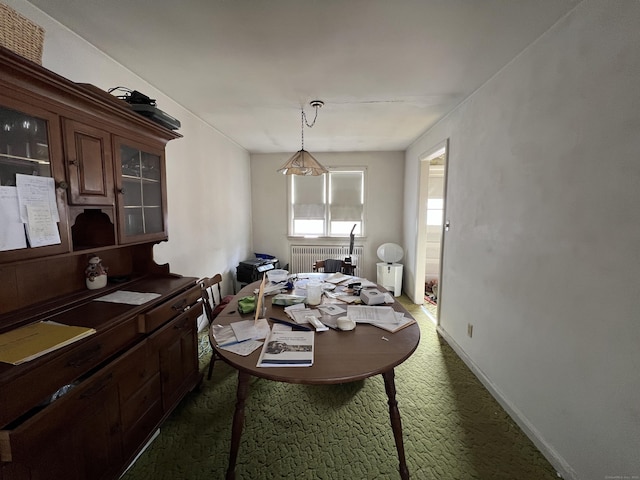 dining space with baseboards, dark carpet, and radiator