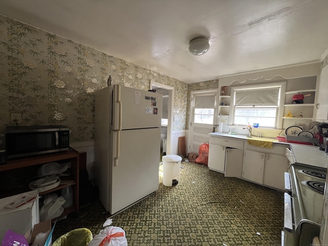 kitchen with open shelves, stainless steel microwave, electric range, freestanding refrigerator, and wallpapered walls