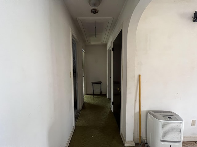 hallway with arched walkways and attic access