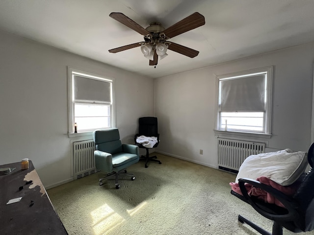 carpeted office space with radiator heating unit, baseboards, and a ceiling fan