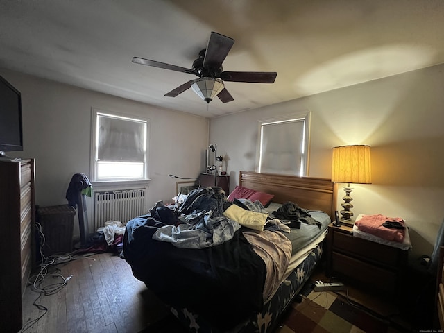 bedroom with hardwood / wood-style floors, radiator heating unit, and a ceiling fan