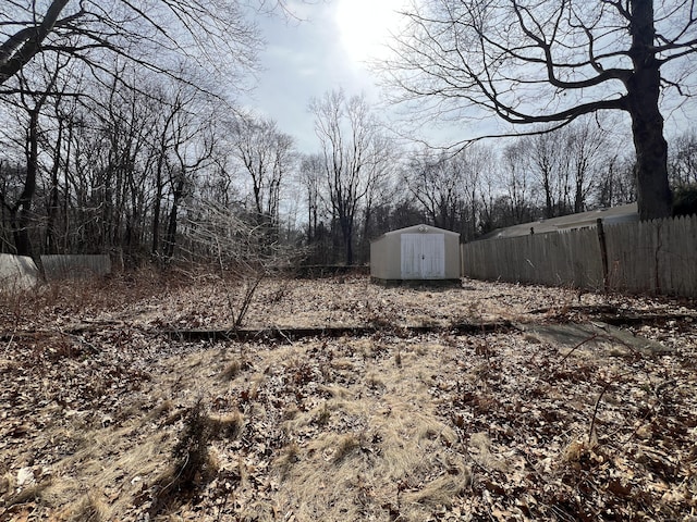 view of yard with a storage unit, fence, and an outbuilding