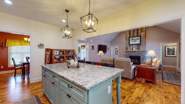 kitchen with light wood-type flooring, lofted ceiling, decorative light fixtures, and a fireplace