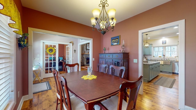 dining area featuring light wood finished floors, a notable chandelier, and a stone fireplace