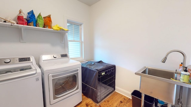 laundry room featuring washer and clothes dryer, a sink, light wood-type flooring, laundry area, and baseboards