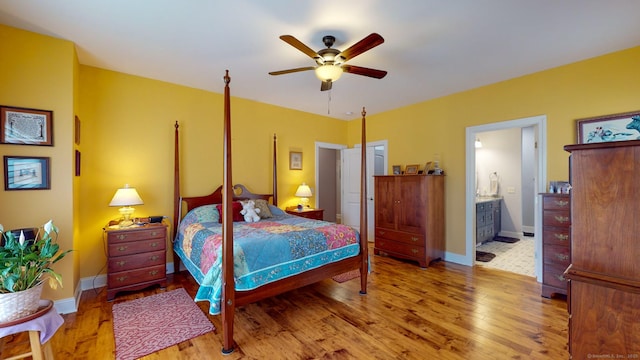 bedroom with a ceiling fan, connected bathroom, baseboards, and wood finished floors