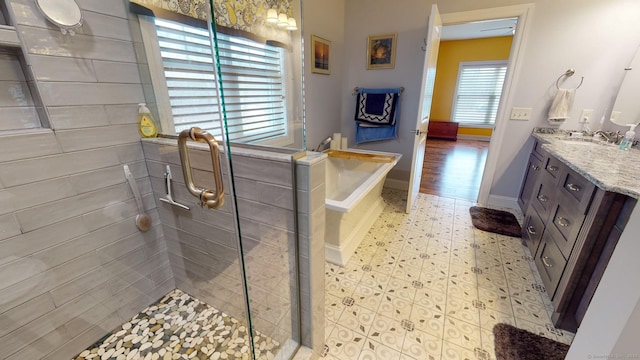 full bathroom with a garden tub, vanity, a shower stall, baseboards, and tile patterned floors