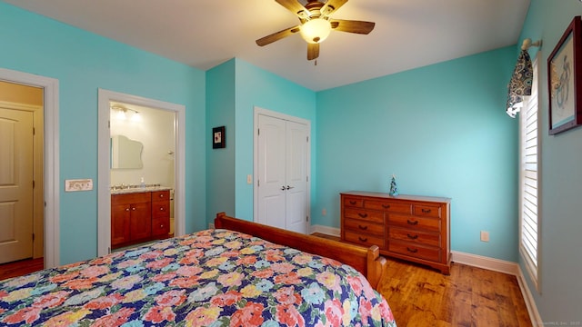 bedroom featuring ensuite bathroom, wood finished floors, a ceiling fan, baseboards, and a closet