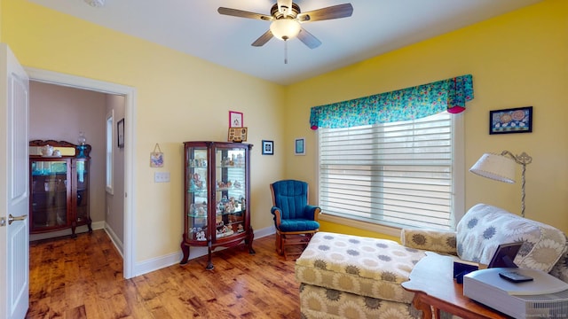 living area with light wood finished floors, baseboards, and a ceiling fan