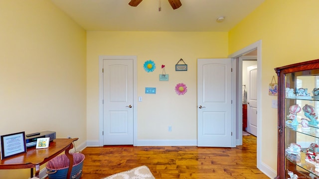 office with a ceiling fan, baseboards, and wood finished floors