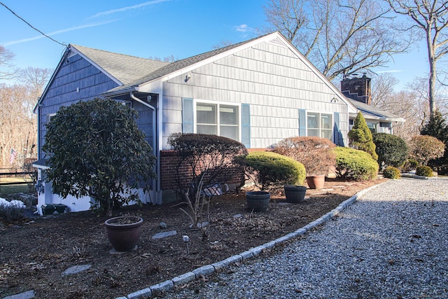 view of property exterior with a shingled roof and a chimney