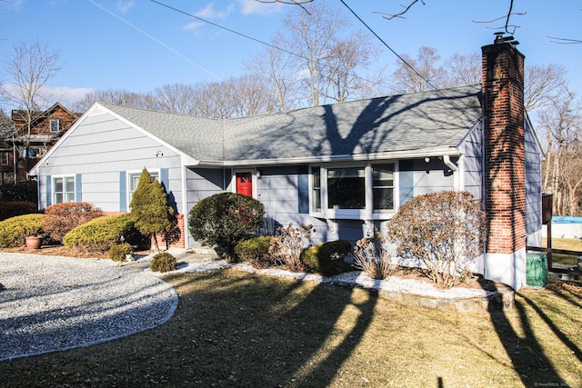 view of front of property with a shingled roof, a chimney, and a front lawn