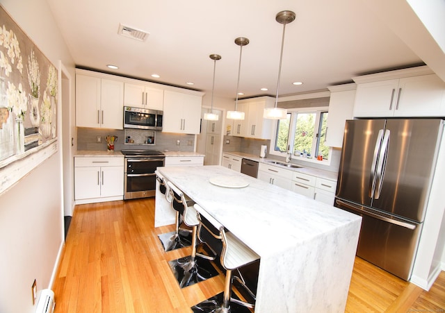 kitchen with white cabinetry, visible vents, stainless steel appliances, and a sink