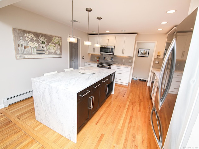 kitchen with tasteful backsplash, white cabinets, a baseboard radiator, appliances with stainless steel finishes, and light wood-type flooring