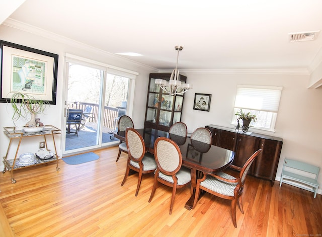 dining area with an inviting chandelier, crown molding, visible vents, and a wealth of natural light