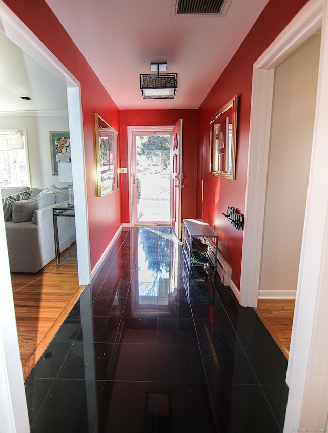 doorway to outside featuring a healthy amount of sunlight, a baseboard heating unit, baseboards, and visible vents