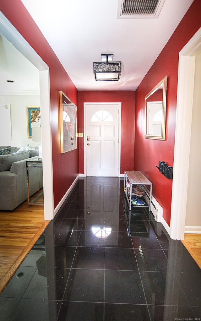 foyer featuring a baseboard radiator, visible vents, granite finish floor, and baseboards