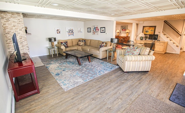 living area featuring stairway, wood finished floors, an ornate ceiling, and baseboards