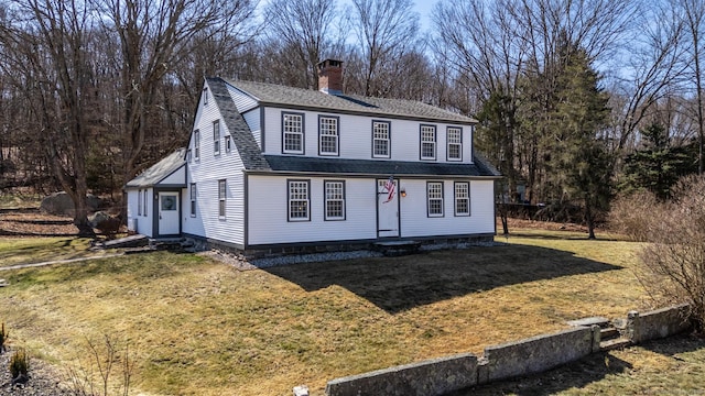 view of front of house featuring a chimney, a shingled roof, a front yard, and entry steps