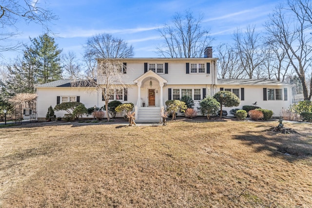 colonial-style house featuring a front yard and a chimney