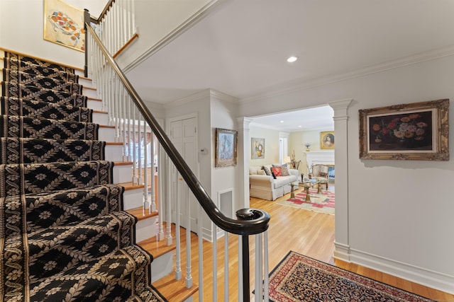 stairs featuring ornate columns, recessed lighting, crown molding, and wood finished floors