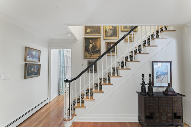 staircase featuring baseboards, a baseboard heating unit, wood finished floors, and ornamental molding