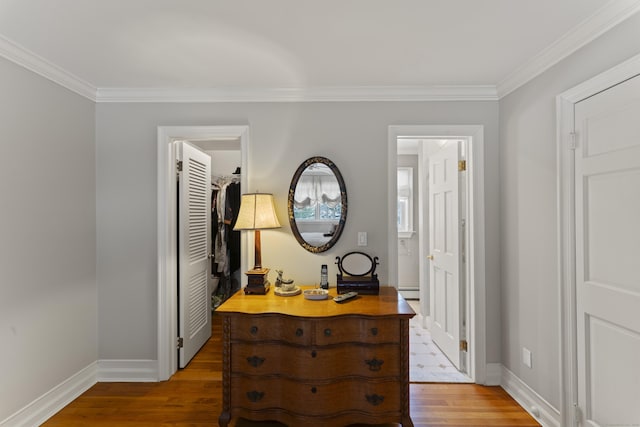 hallway with crown molding, a baseboard radiator, wood finished floors, and baseboards