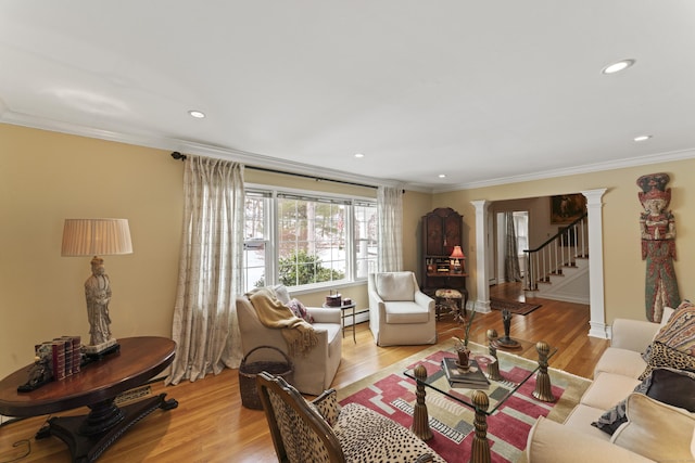 living room featuring decorative columns, recessed lighting, stairway, ornamental molding, and light wood-type flooring