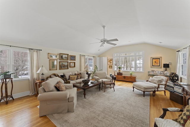 living area featuring light wood-style floors, vaulted ceiling, plenty of natural light, and baseboards