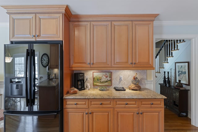 kitchen featuring light stone counters, wood finished floors, black fridge, decorative backsplash, and crown molding