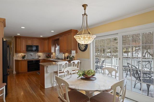 dining space featuring a wainscoted wall, ornamental molding, a wealth of natural light, and wood finished floors