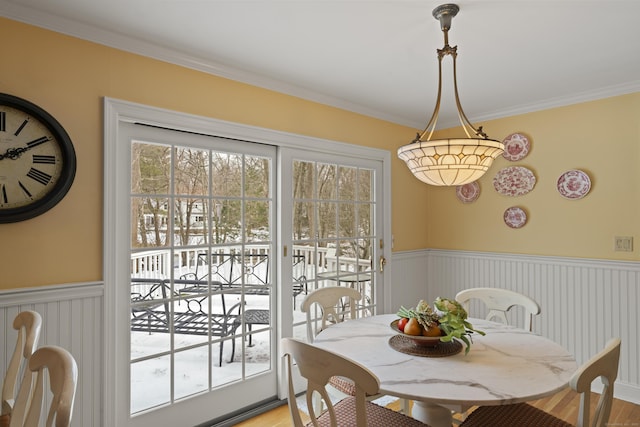 dining area with ornamental molding, wainscoting, and light wood-style flooring