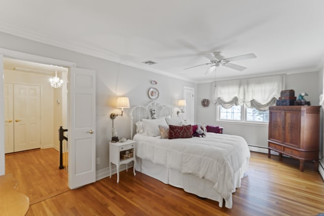 bedroom featuring a ceiling fan, visible vents, crown molding, and wood finished floors