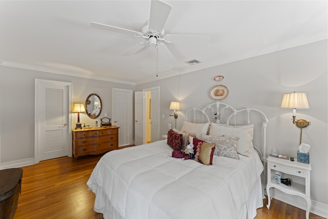 bedroom with baseboards, visible vents, wood finished floors, and ornamental molding