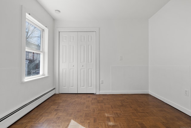 unfurnished bedroom featuring baseboards, baseboard heating, and a closet