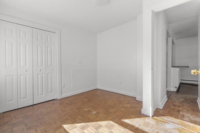 unfurnished bedroom with baseboards, baseboard heating, and a closet