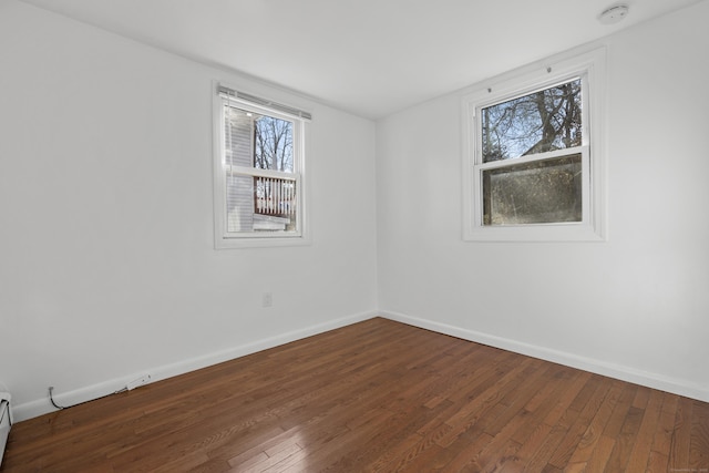 spare room featuring wood-type flooring and baseboards