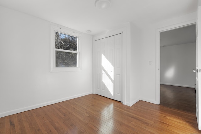 spare room featuring wood-type flooring and baseboards