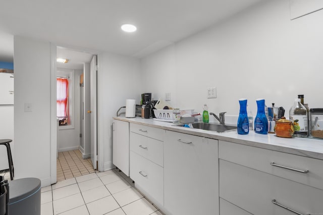 kitchen with baseboards, white cabinets, light countertops, a sink, and light tile patterned flooring