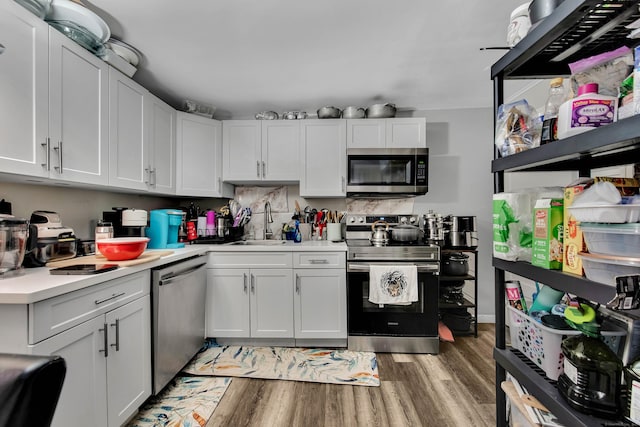 kitchen featuring light countertops, appliances with stainless steel finishes, white cabinetry, a sink, and light wood-type flooring