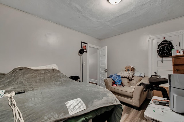 bedroom with a textured ceiling and wood finished floors