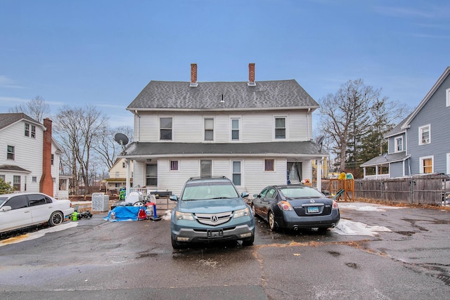 view of front of property featuring a shingled roof, a chimney, and fence