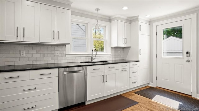 kitchen with crown molding, dark wood finished floors, dark countertops, a sink, and dishwasher