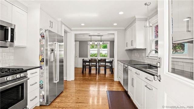 kitchen with dark countertops, light wood-style flooring, appliances with stainless steel finishes, and a sink