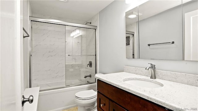 bathroom with toilet, combined bath / shower with glass door, and vanity